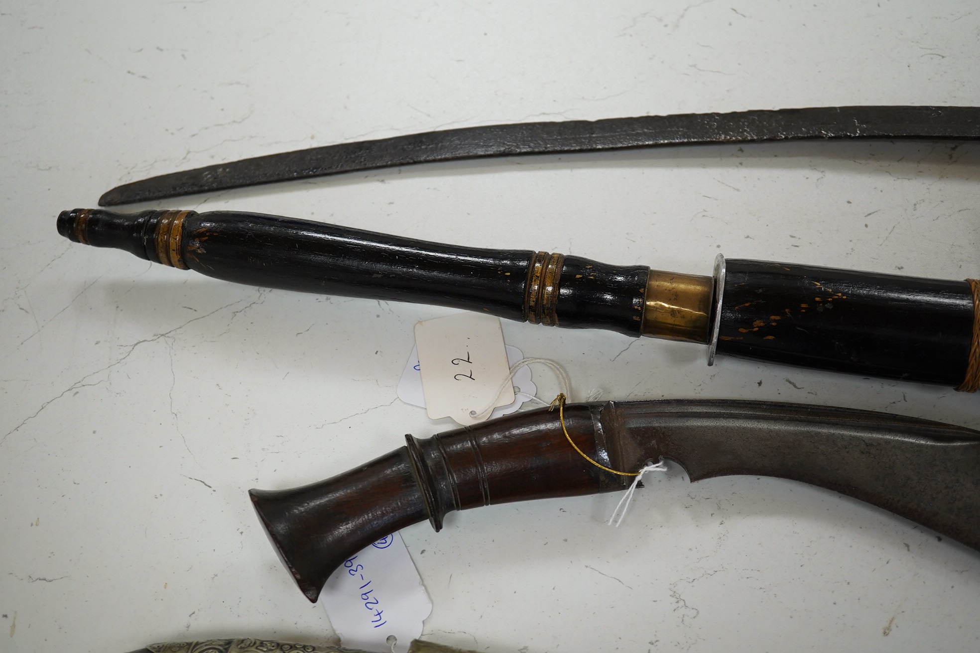 Four bladed weapons; an Indian sword Tulwar, blade 68.5cm. Condition - poor, heavily pitted., A Nepalese Kukri. Condition - fair., A Thai sword Dha, with a lacquered hilt and wooden scabbard, blade 56cm. Condition - fair